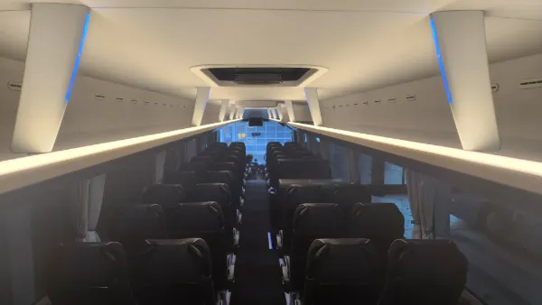 Reisebus-Innenraum mit dunklen Sitzreihen, Deckenmonitor und LED-Lichtleisten