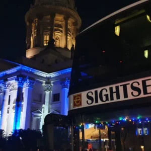 Sightseeingbus vor einer beleuchteten Berliner Kirche bei Nacht